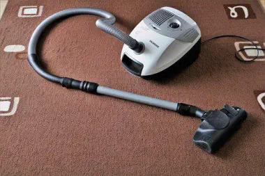 Foto, ein Staubsauger liegt auf dem Teppichboden